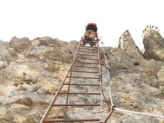a man climbs a ladder at the summit of a mountain