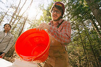 A student in the woods pouring water from one container to another