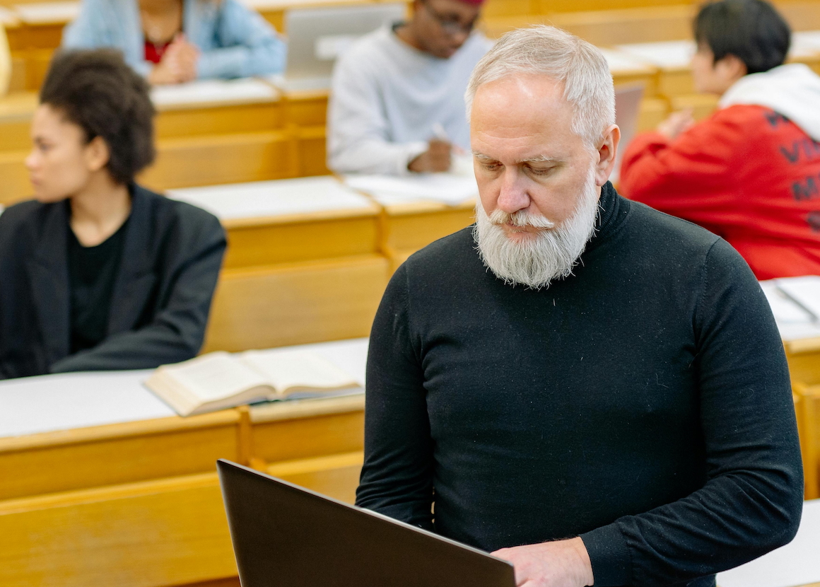 Professor_looking_at_computer_program_viability_playbook