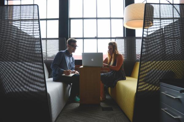 two people sitting across from one another looking at a laptop