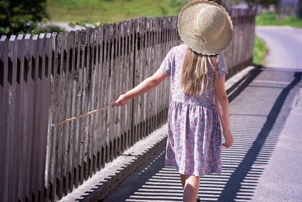 little girl walking with a stick in had