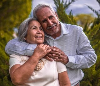 An older man with his arm wrapped affectionately around an older woman