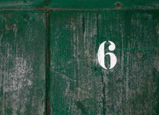 The number six on a green wooden background
