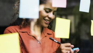 A woman writes on a post-it note