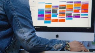 A woman looks at a calendar on a desktop monitor