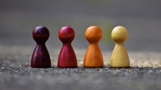 Four wooden game pieces resembling chess pawns, each a different color