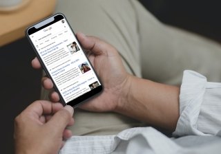 A man searches Google for "best nursing schools" on his mobile phone