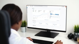 A woman sits at a desk reviewing analytics data