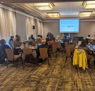 A speaker at a podium delivering a keynote to attendees at the Raleigh OHO U In-Person Bootcamp