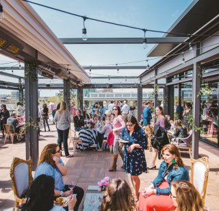A group of people enjoying a summer day outside on the terrace at the District Winery