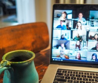 Open laptop with a Zoom meeting on the screen and a cup of coffee.