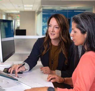 two colleagues reviewing their university website in an office setting